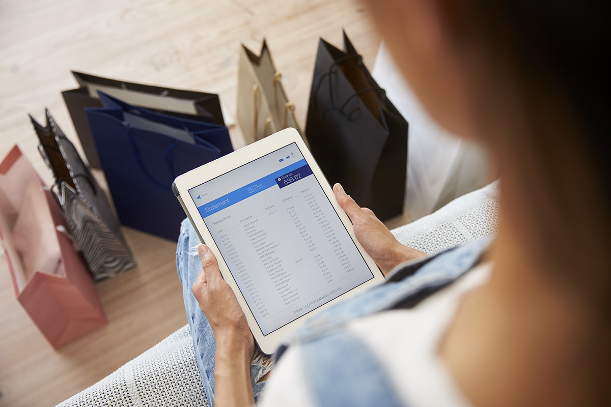 Woman With Shopping Bags Checks Bank Statement On Pqshu9z