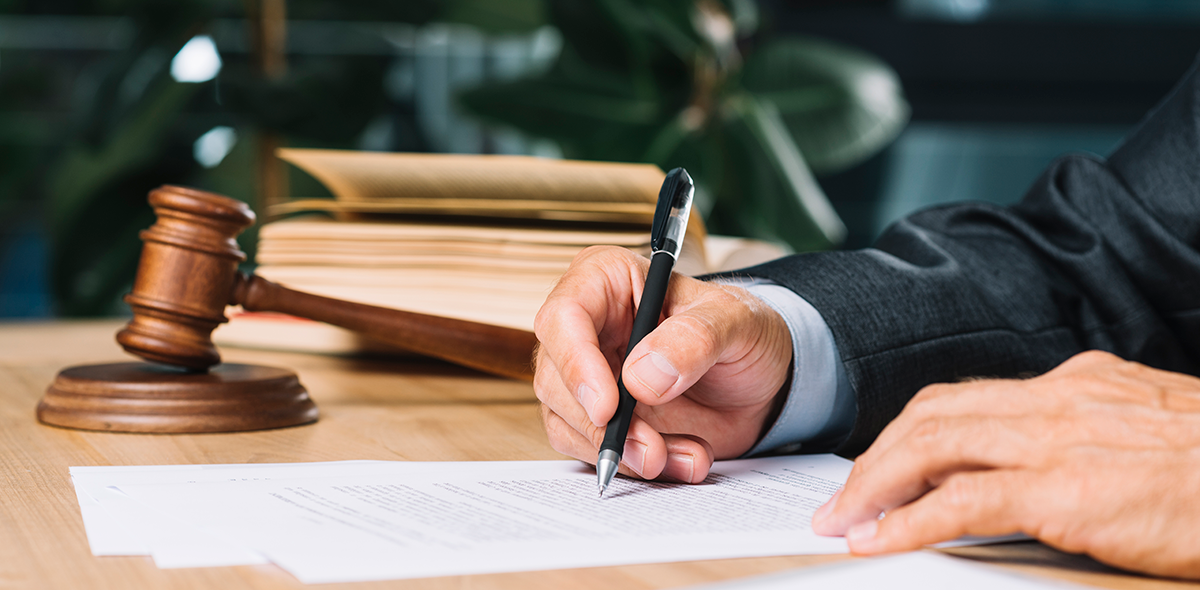 Judge Holding Pen Checking Document Over Wooden Desk